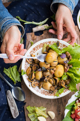 Woman hands holding backed potatoes and roasted mushrooms on salad leaves. Organic farm lunch or dinner. Raw vegan vegetarian healthy food