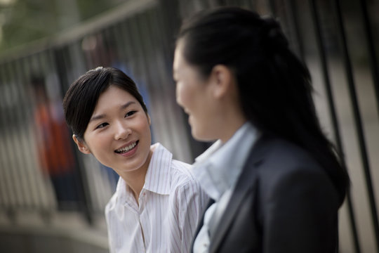 Smiling young businesswoman speaking with a colleague.