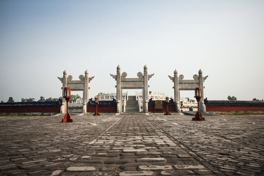Three traditional gates in a paved courtyard.