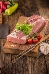 Pork loin fillet parsley herb tomatoes pepper garlic salt and spices on wooden kitchen board.