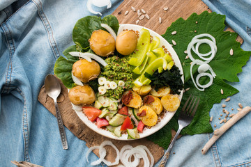 Buddha bowl with backed potato, seaweed, vegetables, spinach leaves, pesto dip sauce, salad, garlic. Raw vegan vegetarian healthy food on lunch or dinner