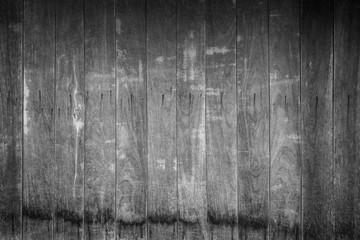 Full frame background of an old and faded wooden board wall with vignette in black and white