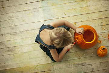 Little boy carving Halloween pumpkin