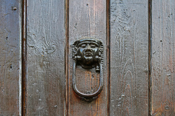 Door knocker with human head on wooden door in Girona (Catalonia, Spain)