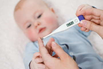 Woman measuring temperature of small sick boy