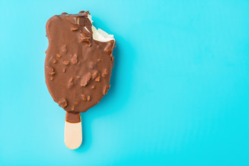 top view chocolate outer ice cream with a bite on a blue background close up