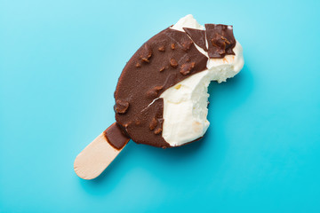 top view chocolate outer ice cream with some bites on a blue background close up
