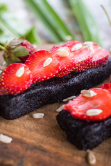 Raw vegan energy bars with strawberry pieces. Candies with dates, dark cocoa, sunflower seeds. Healthy sweet chocolate dessert. Vegetarian food