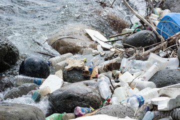 Plastic drum floating on a beach side and other flowing plastic garbage