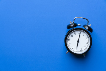 Retro alarm clock on blue background, vintage style