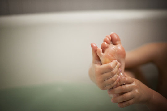 A boy's wet hands and feet as he takes a bath