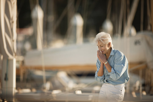 Senior woman smiles while standing at a marina.