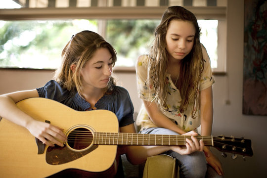 Teenage girl playing her guitar with a friend.