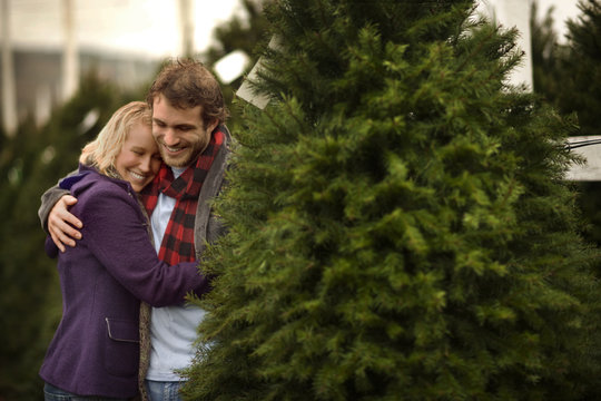 Happy couple sharing a moment at a Christmas tree farm.