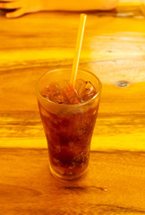 Cold soft drinks in glass with ice on a wooden table.
