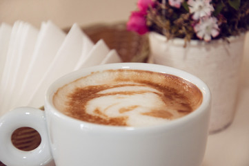 Appetizing coffee in a white cup on a table indoors, close-up