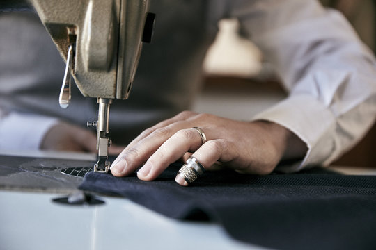 Man using industrial sewing machine to stitch garment