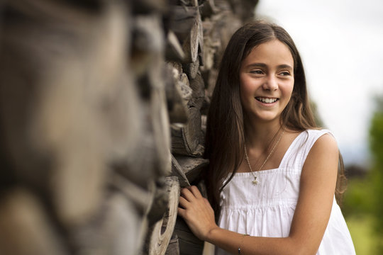 Portrait Of Young Girl Next To Stack Of Firewood.