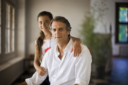 Portrait of girl standing with arm around her father.