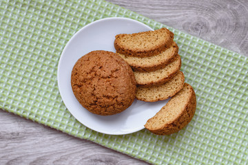 Homemade cookies on a white saucer and green napkins on a wooden background