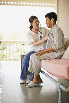 Nurse listening to her elderly patient's heartbeat with stethoscope.