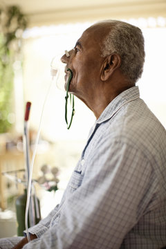 Unwell elderly man uses oxygen mask.