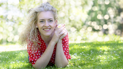 Blond woman with flowers in a park in summer.
