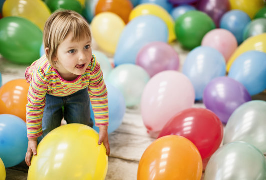Little girl having fun in a room full of balloons.