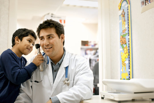 Boy examining his doctor's ear with otoscope