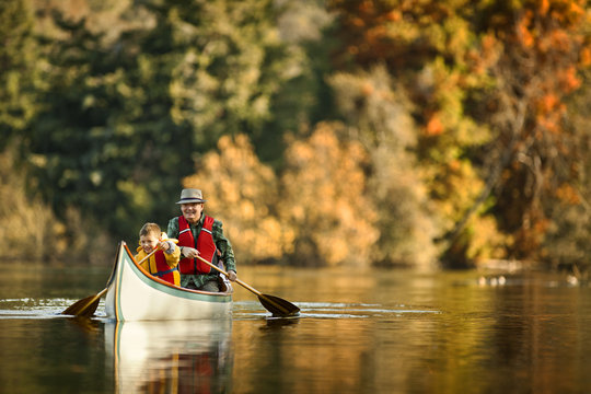 Grandfather canoeing on river with grandson.
