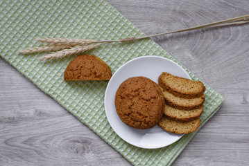 Homemade cookies on a white saucer and green napkins, spikelets of wheat on a wooden background