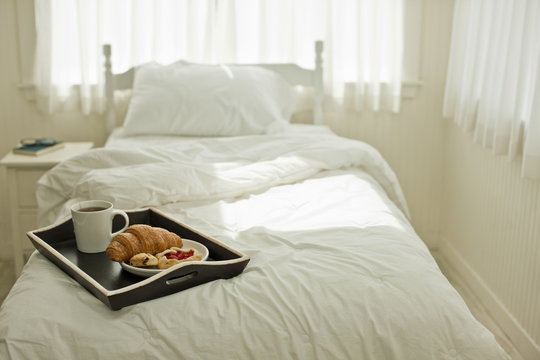 Breakfast tray of tea and pastries on top of a bed.