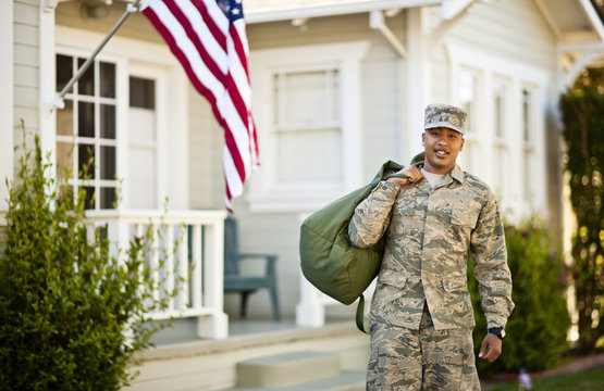 Portrait of young soldier standing outside his home