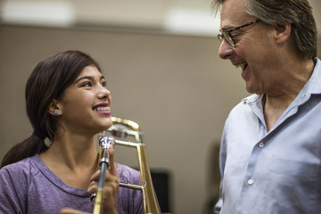 Teenage girl learning to play trombone at music class
