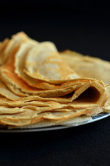 Thin pancakes on black background