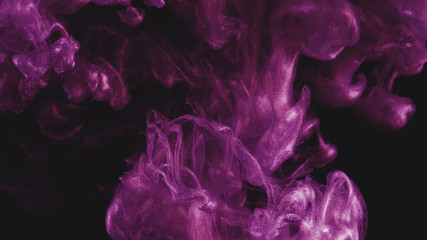 Ink in water. Colour pink glitter paint reacting in water creating abstract cloud formations.