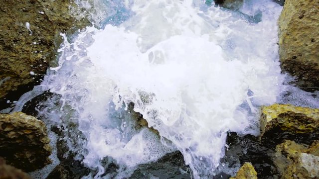 Water from sea hitting against rocks, slow motion