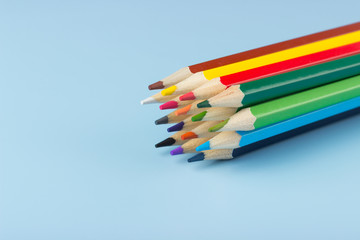 A bunch of colored pencils lying on a blue background.