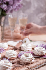 Delicious marshmallow cakes with champagne on the wooden background with flowers.