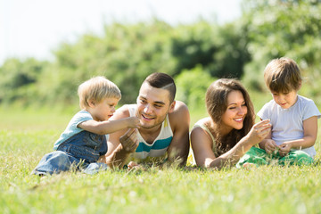 Naklejka na ściany i meble Family of four in grass at park