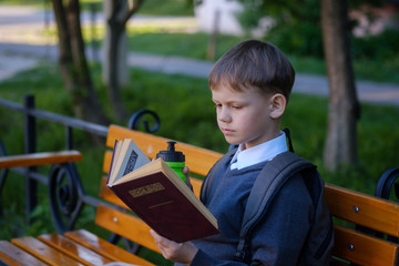 European boy eats school Breakfast on the Park bench