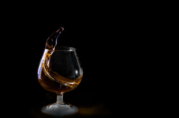 Splash of white wine in a glasson. Black background