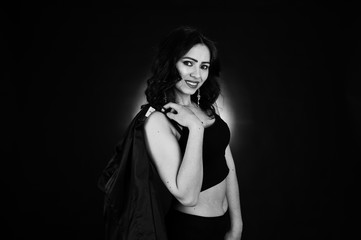 Naklejka premium Studio portrait of sexy brunette girl in black leather jacket against black background.