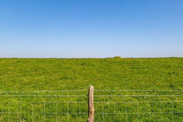 Fototapeta premium A barbed wire fence with a wooden post, in the Sussex countryside