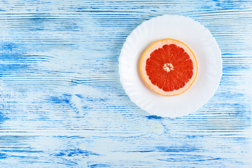 A fresh grapefruit on a white plate on a wooden background