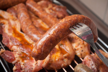 closeup of sausages and pork belly on the barbecue