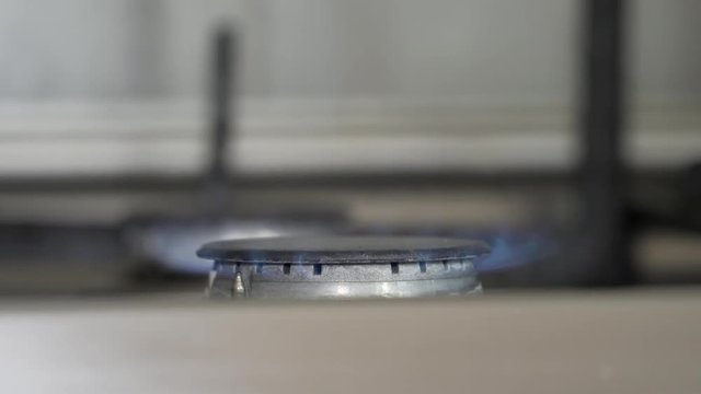 Turning on and burning gas burner on the stove. Close up. Blue flames