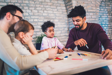 Two fathers play educational games with their children, having fun.