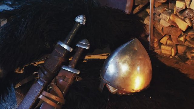 A close-up of a Viking helmet and two swords in a scabbard.