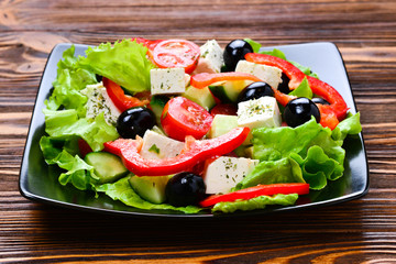 Greek salad on a wooden background. Space for text or design.